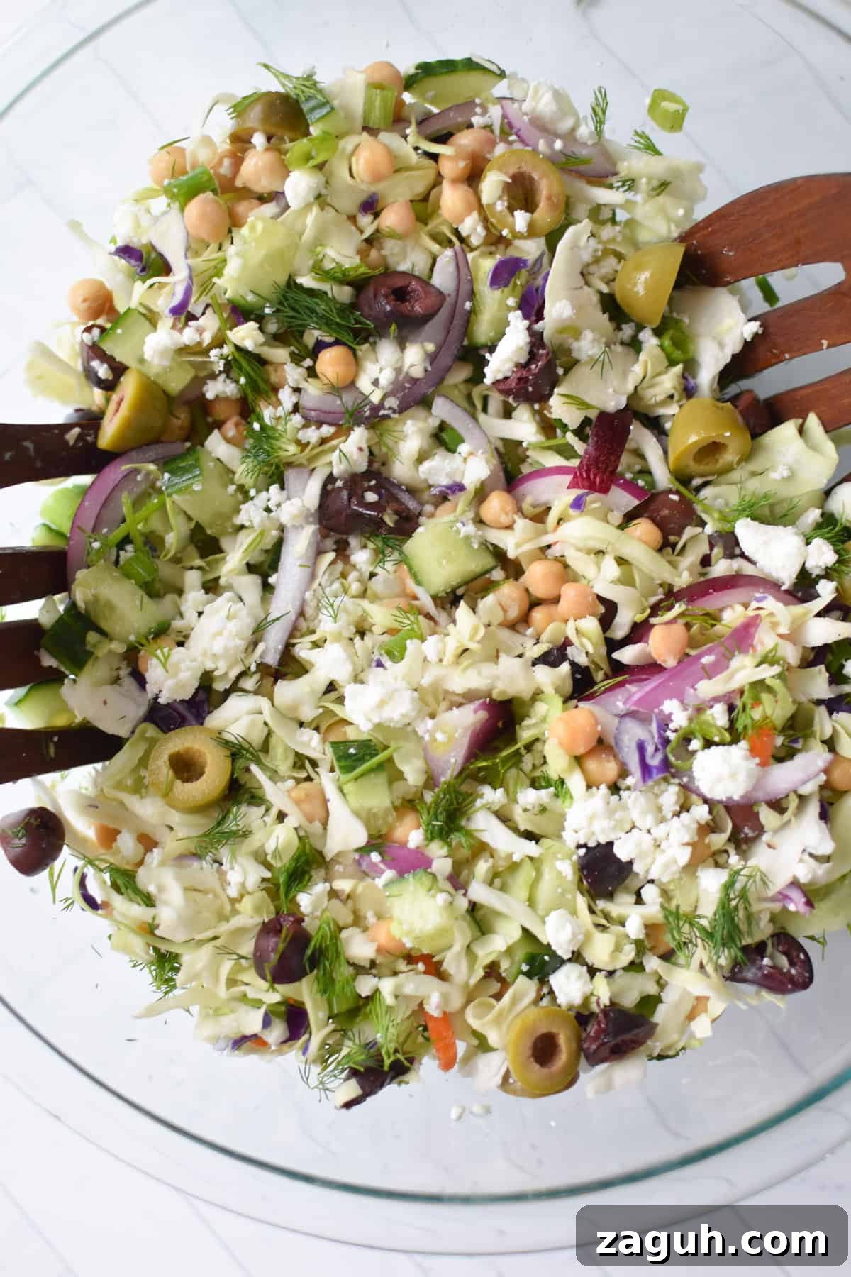 Greek Cabbage Salad Recipe with Feta and Lemon Dressing 6 Greek Cabbage Salad in a clear glass bowl with serving spoons