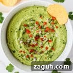 Guacamole in a bowl with diced tomatoes and onions on top.