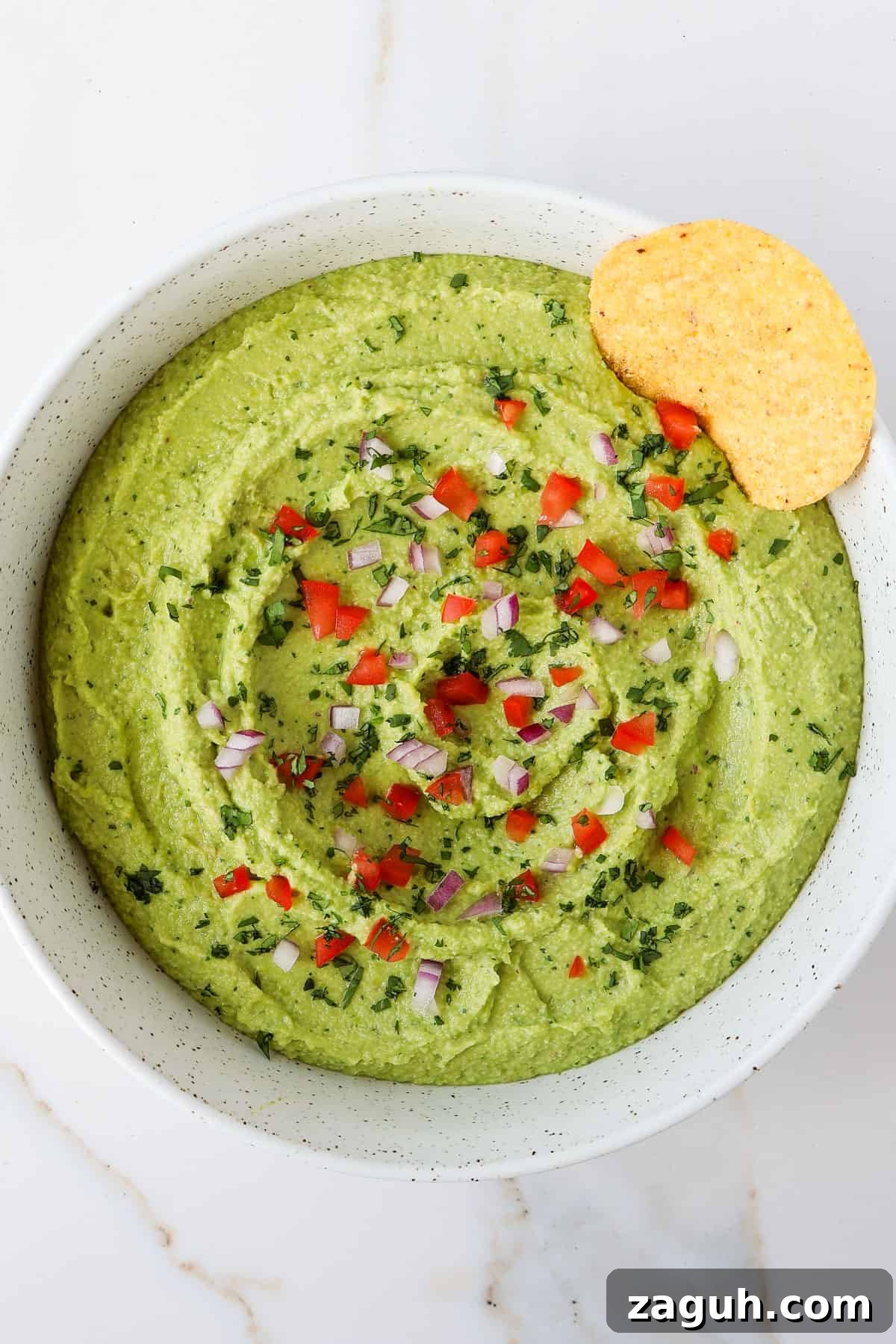Protein-Packed Edamame Guacamole Recipe for Muscle Fuel 10 Guacamole in a bowl with a tortilla chip.