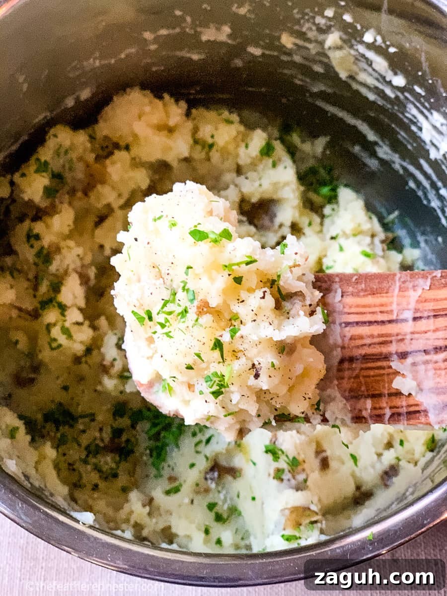 Instant Pot Mashed Potatoes Without Draining 8 A wooden spoonful of mashed potatoes garnished with fresh parsley.