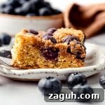 Moist Blueberry Sour Cream Coffee Cake Recipe 24 A slice of blueberry sour cream coffee cake on a plate with a fork.