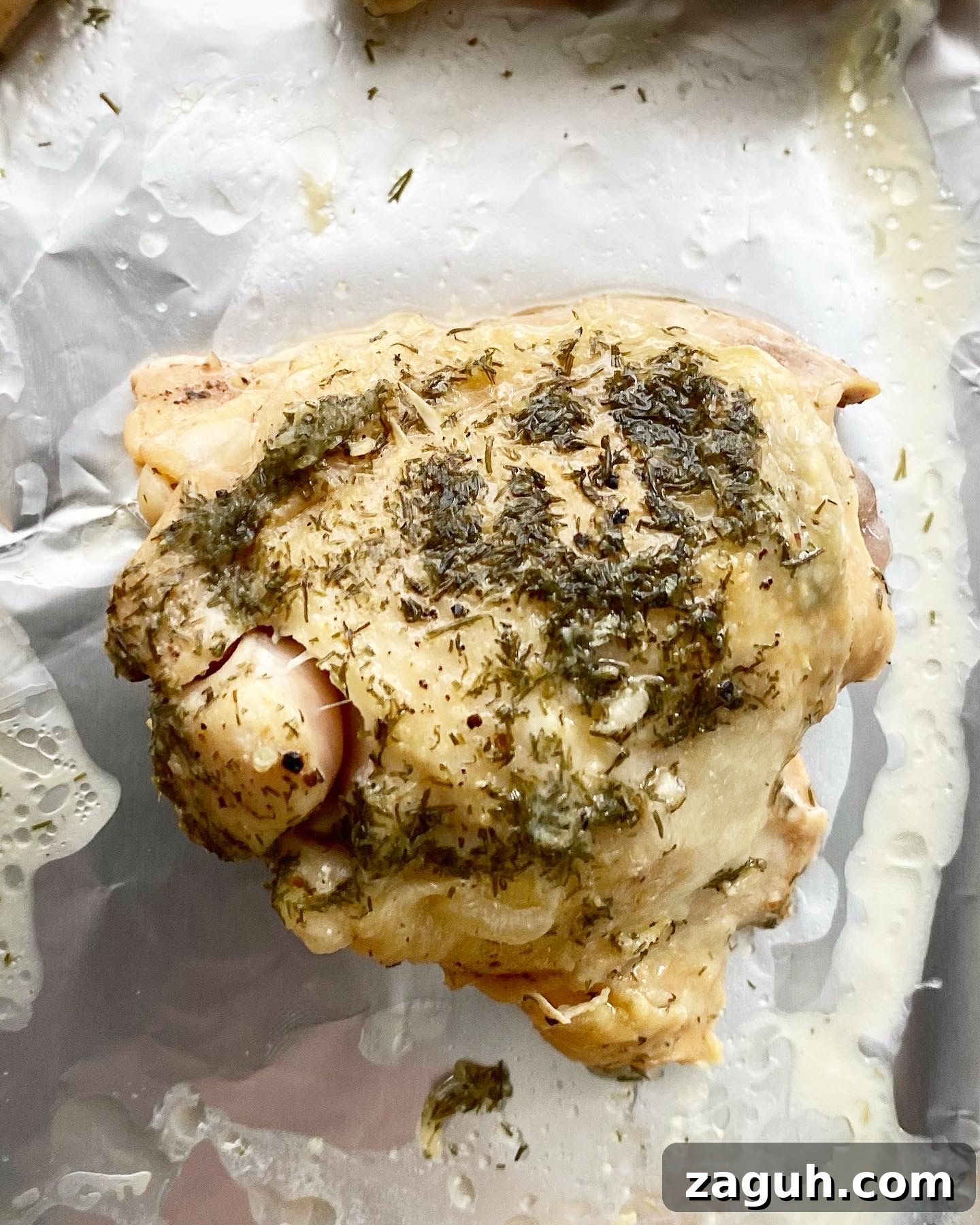 Creamy Lemon Dill Chicken for Slow Cooker: Tender, Flavorful Meal 6 overhead shot of cooked chicken thigh on a foil-lined baking sheet