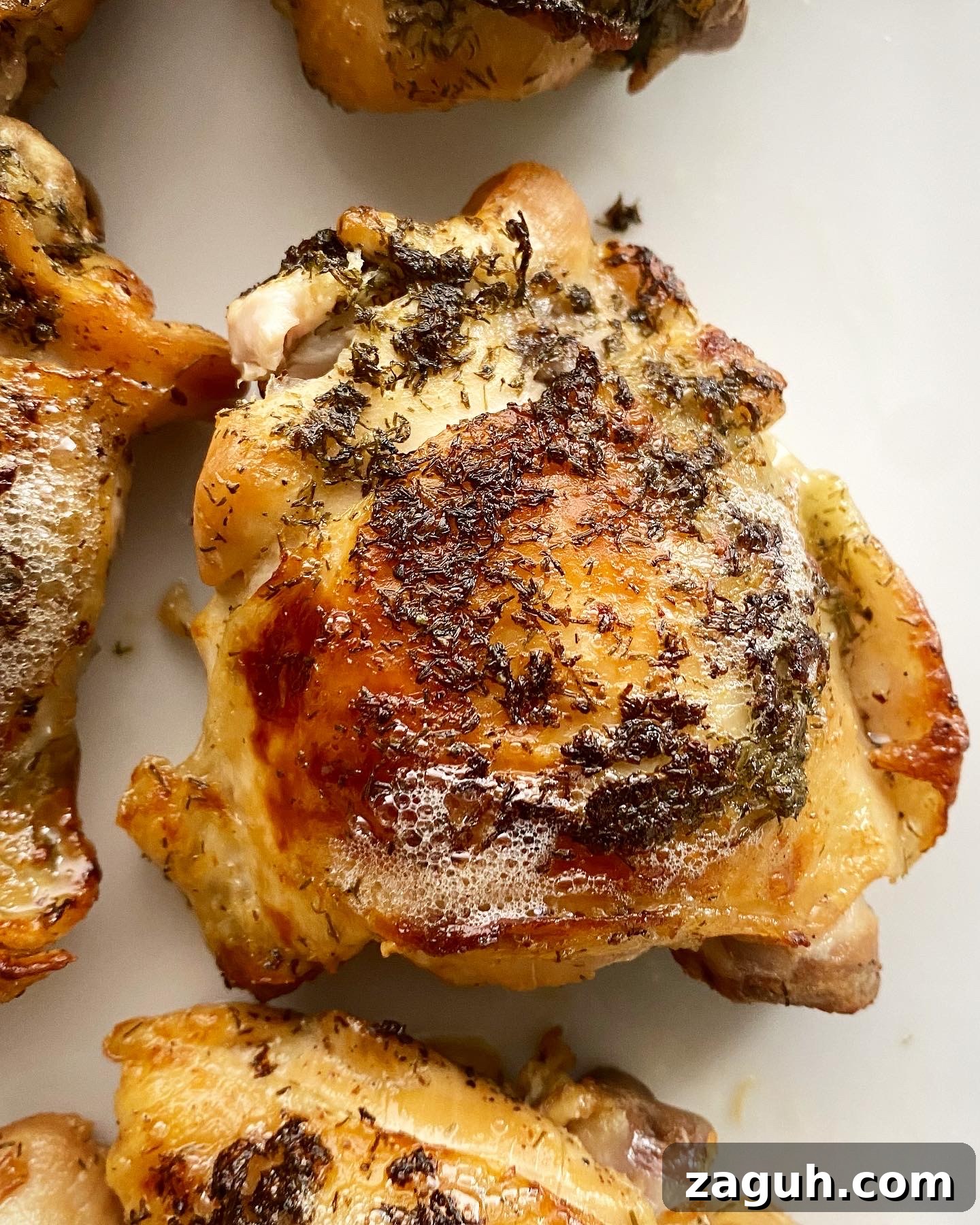 Creamy Lemon Dill Chicken for Slow Cooker: Tender, Flavorful Meal 7 overhead shot of cooked, broiled crispy chicken thigh on a foil-lined baking sheet