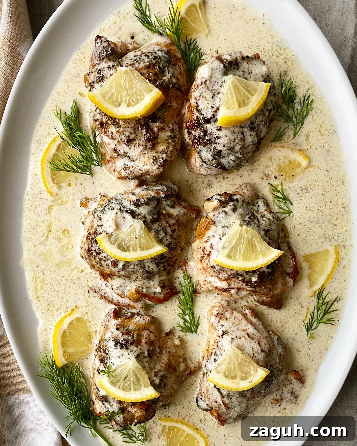 Creamy Lemon Dill Chicken for Slow Cooker: Tender, Flavorful Meal 8 overhead shot of crockpot creamy lemon dill chicken on a white platter garnished with lemon slices & fresh dill