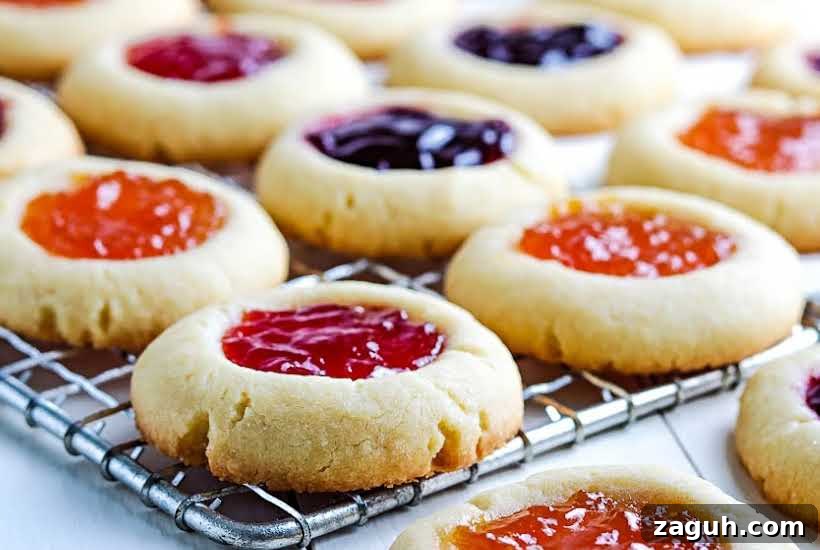 Strawberry Jam Thumbprint Cookies: Soft, Fruity Recipe 6 close up of finished strawberry jam cookies and other flavors on wire cooling rack.