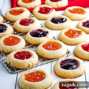 Strawberry Jam Thumbprint Cookies: Soft, Fruity Recipe 8 strawberry jam cookies on a wire cooling rack with some on the counter