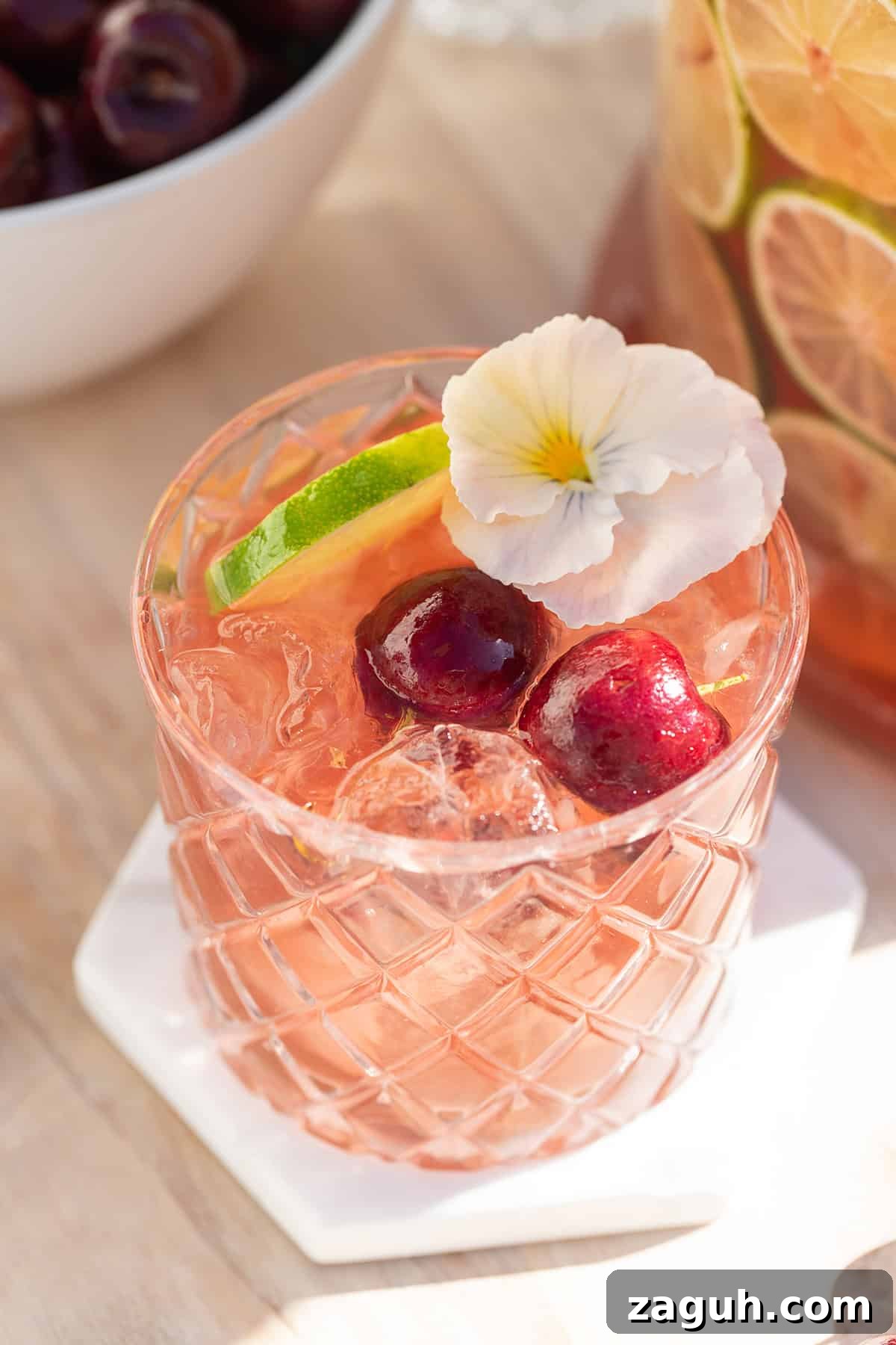 Sparkling Cherry Punch Recipe for Parties and Summer Gatherings 3 Cherry gin and tonic punch with fresh cherry juice and tonic water in a glass with a lime wedge.