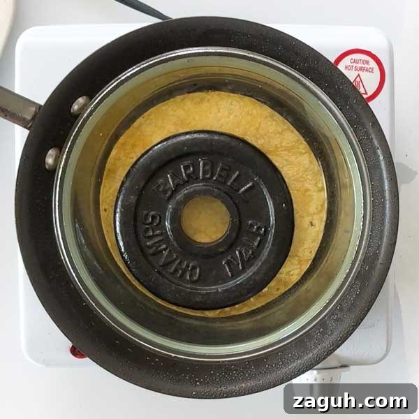 Gluten-Free Big Mac Smashed Tacos Recipe That Went Viral 11 Placing a glass bowl with a weight inside on top of the meat and tortilla in the skillet.