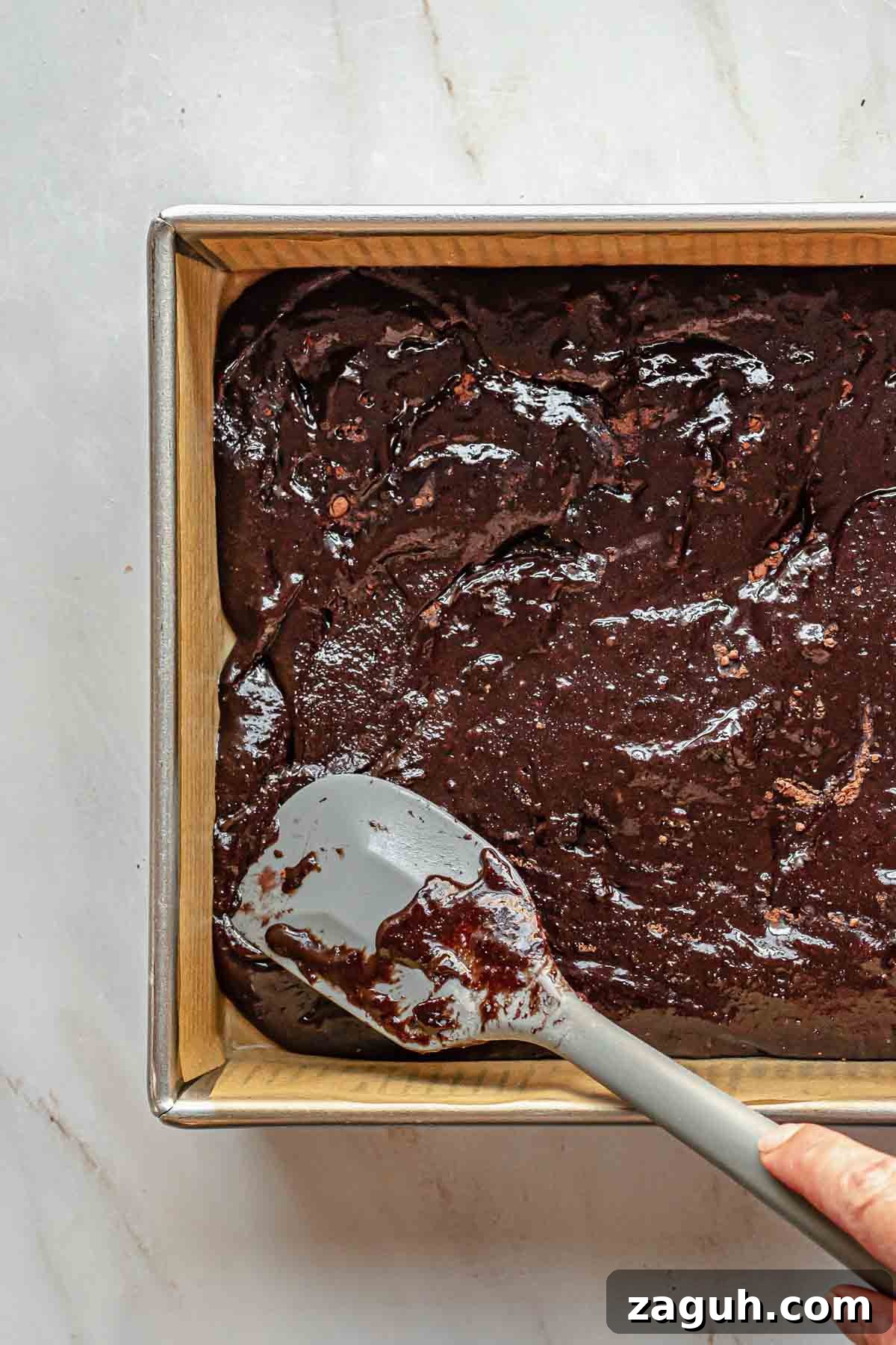 Ferrero Rocher Chocolate Brownies Recipe: Decadent Hazelnut Treat 12 A spatula spreads the brownie batter to the edges of the pan.