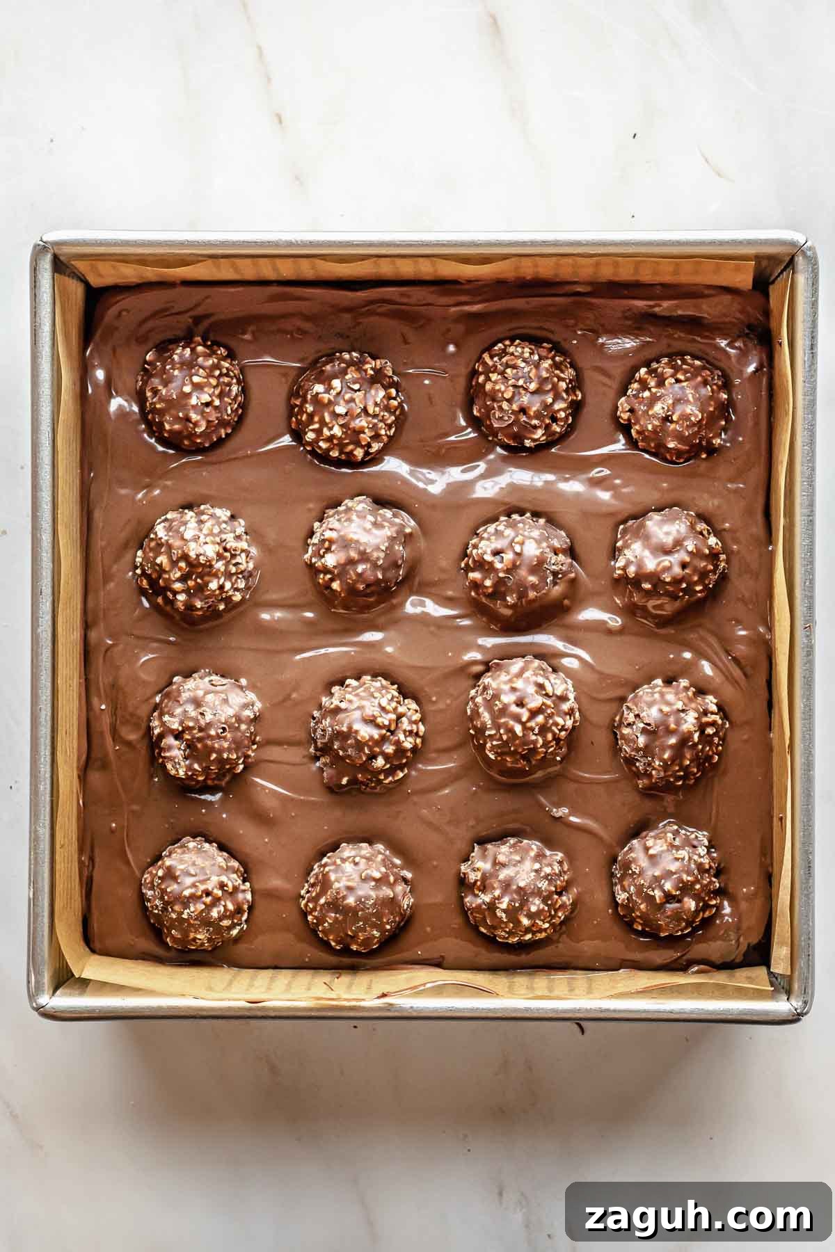 Ferrero Rocher Chocolate Brownies Recipe: Decadent Hazelnut Treat 14 16 Ferrero rocher balls on top of the Nutella and brownie batter in a pan.