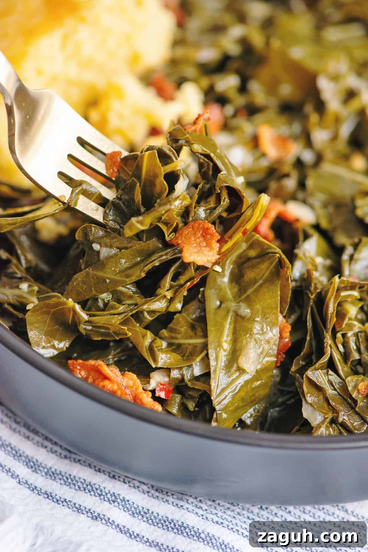 Authentic Southern Collard Greens Recipe That Melts in Your Mouth 4 A forkful of collard greens hovering over a black bowl.