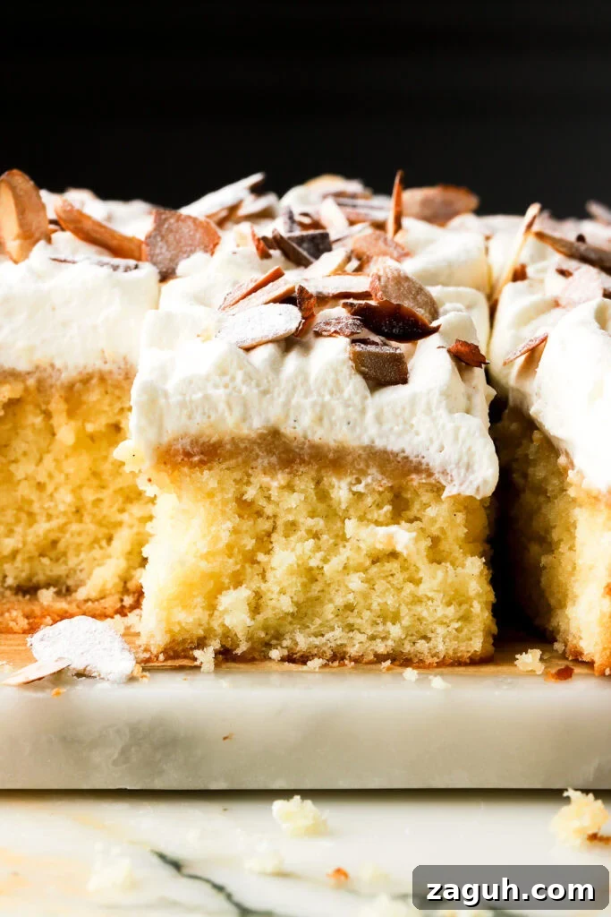 almond croissant sheet cake sliced and showing the inside, topped with toasted almonds and black background