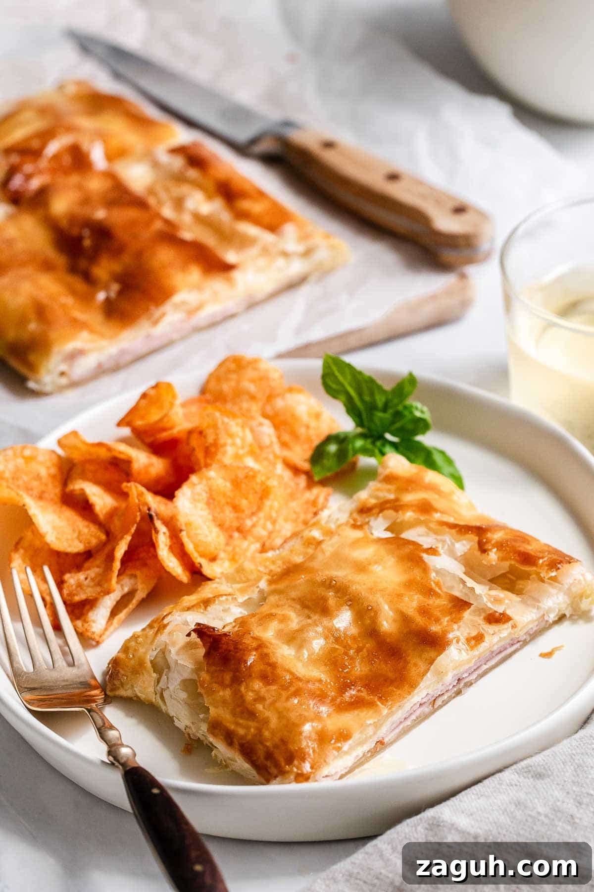 Perfect Puff Pastry Dough: Step-by-Step Homemade Recipe 10 Ham and cheese puff pastry square on a plate with chips.