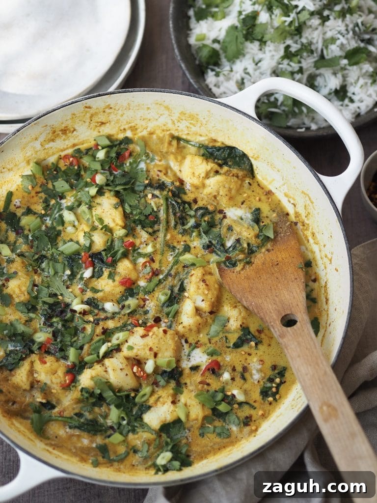 Quick Coconut Fish Curry with Lemongrass and Lime 2 White shallow casserole dish with a fish and spinach curry next to serving bowls and a bowl of herbed rice.